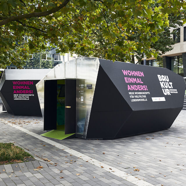 Die Ausstellung „WOHNEN EINMAL ANDERS!“ auf dem Kesselbrink in Bielefeld. Außenansicht auf die beiden temporären Pavillon-Architekturen aus Holz.